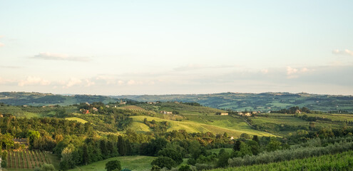 Obraz premium The Evening view of a green authentic valley in the Tuscany region of Italy In the distance, many houses, vineyards and other plants can be seen