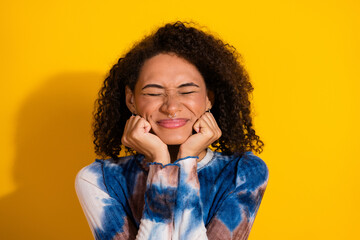 Young happy woman with cheerful expression posing against a vibrant yellow background, dressed...