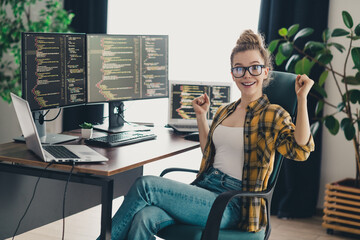 Young programmer wearing casual attire celebrating a coding success in a modern home office...