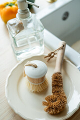 Plate with an ecobrush for washing dishes near the sink, soap in a glass bottle, a towel.