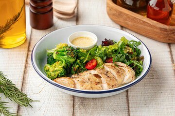 Healthy lunch bowl with grilled chicken, fresh salad and broccoli on rustic wooden table