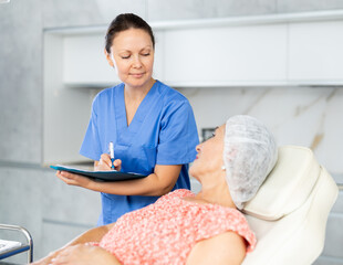 Obraz premium Female cosmetologist writes down the complaints of female patient in a cosmetology clinic