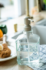 Plate with an ecobrush for washing dishes near the sink, soap in a glass bottle, a towel.