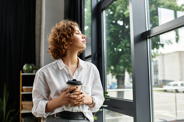 Young businesswoman in a modern office reflecting on her day while enjoying coffee