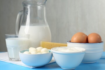 Different dairy products and eggs on light blue wooden table, closeup