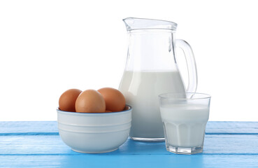 Milk and eggs on blue wooden table against white background