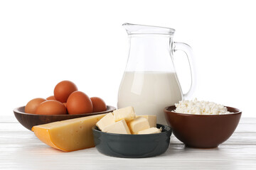 Different dairy products and eggs on wooden table against white background