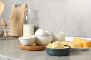 Different dairy products and eggs on gray textured table in kitchen