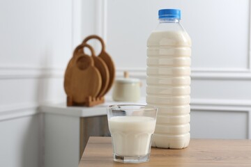Bottle and glass of milk on wooden table indoors. Space for text