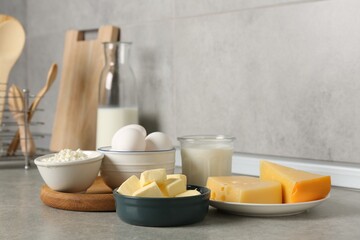 Different dairy products and eggs on gray textured table in kitchen
