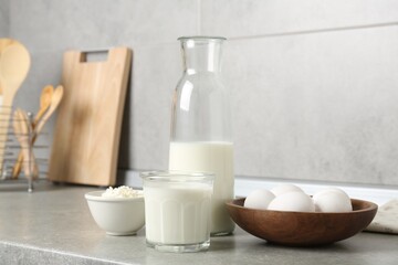 Different dairy products and eggs on gray textured table in kitchen