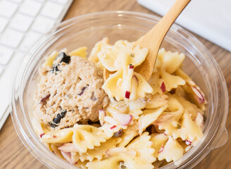 Creamy Tuna Farfalle Pasta Salad in Clear Bowl with Wooden Spoon closeup view of quick meals