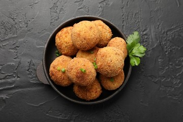 Delicious fried croquette balls with green onion and parsley on grey textured table, top view