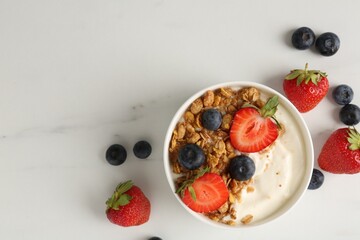 Tasty yogurt with granola and berries on white marble table, flat lay. Space for text