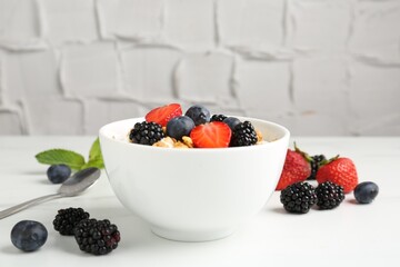 Tasty yogurt with granola and berries in bowl on white table, closeup