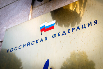 The flag and inscription of the Russian Federation at the entrance to the government building in the country..