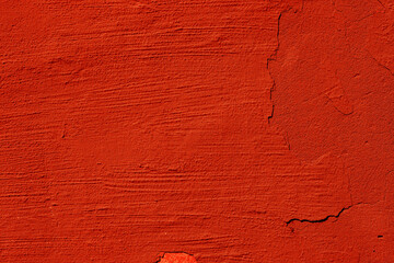 A concrete wall with cracked red plaster. The texture of an abandoned wall.