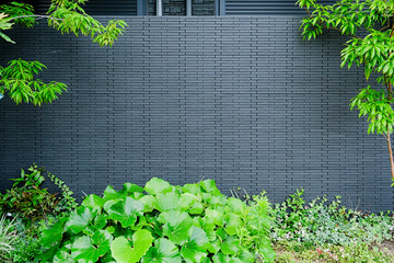 Brick wall with gray bricks and lush green bushes