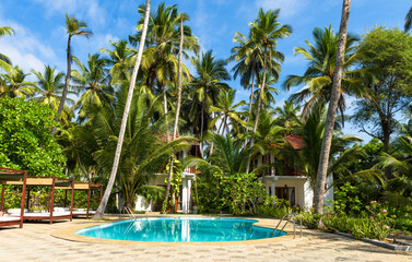 Tropical hotel with pool amidst lush palm trees and clear blue sky, concept of travel, resort,...