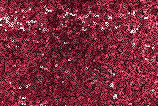 Texture of shiny fabric with sequins. Luxurious red background decorated with sequins.