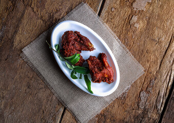 Spicy Fried Chicken on Rustic Wooden Surface with Fresh Green Garnish