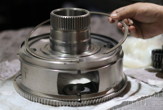 Close up hand disassembling retaining ring or snap ring on planetary gear of automatic transmission.