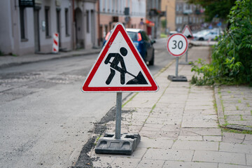Temporary road work warning sign and speed limit on urban street during city infrastructure maintenance