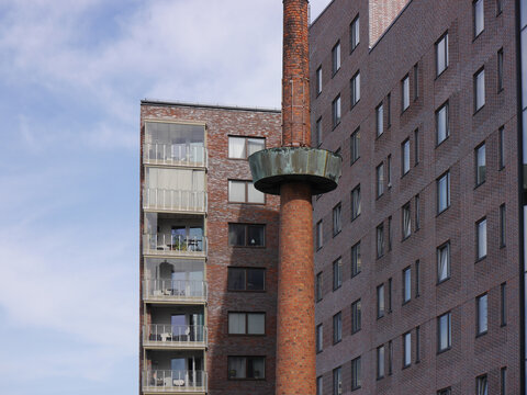 An old chimney in front of modern buildings.