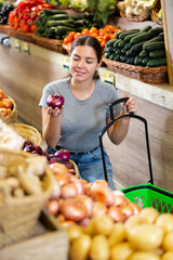 Caucasian woman looking to buy red onions in local fruit and vegetables market