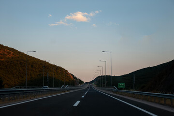 Sunrise in the morning road. Empty long mountain road to the horizon on a sunny summer day at...