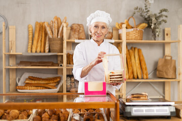 Elderly woman baker offers to buy a fresh delicious sweet cake