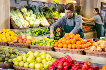 Male salesman near fruit and vegetables stalls offering to buy limes