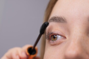 Young Woman Applying Mascara to Enhance Eyelashes. 