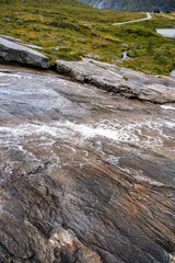 Dynamic Mountain Stream Cascading Over Polished Rock Formations in Lush Green Nordic Landscape - Nature's Erosion Art