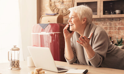 Unexpected Call. Surpised Aged Woman Talking On Cellphone In Kitchen And Emotionally Gesturing