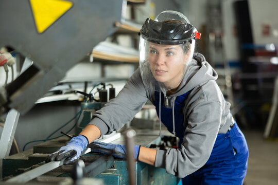 During production of glass products, woman employee wearing clear protective face shield controls production process and is in area of operating equipment.
