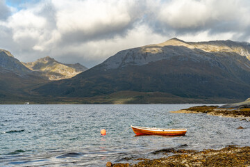 Traditional Wooden Rowboat on Calm Water with Dramatic Mountains: Remote Nordic Fjord/Lake Landscape