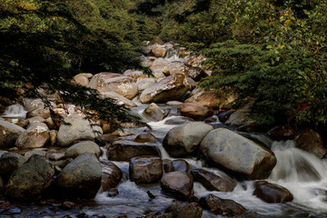 Río de montaña cristalino en San Rafael, Antioquia, Colombia, con rocas pulidas y vegetación exuberante. Belleza natural serena, agua pura fluyendo entre piedras. Paisaje fluvial vibrante para ecoturi