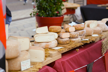 Various artisan cheeses displayed on a rustic market stall with natural straw and wooden boards