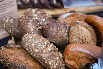 Close up of artisanal whole grain bread loaves with seeds and oats at local food market stand