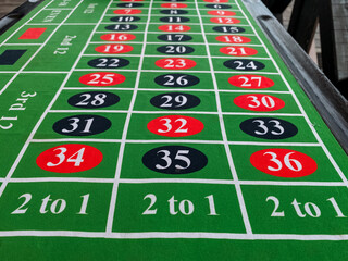 A vibrant and visually striking green roulette table adorned with a variety of red and black...