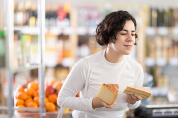 In store, woman near counter looking at varieties of cheese. Visitors make choice of assortment,...