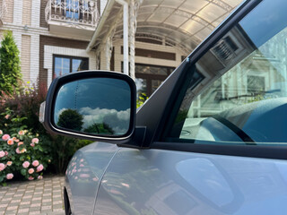 A beautiful car side mirror reflects a stunning residence, highlighting its carefully designed...