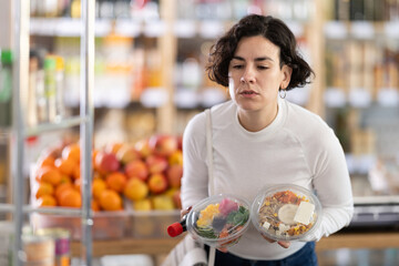 Woman choosing prepared Hawaiian food poke salad, doubt and think before buying. Client choose...