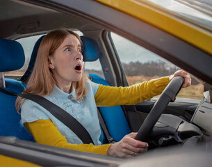 young woman getting shocked driving a car. Front view portrait of an scared driver driving a car before an accident. Fright and fear on the face. High quality photo