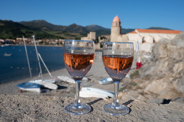 Glasses of rose Collioure AOC wine in sunlights with view on old town Collioure, colorful houses, church, castle and beaches, Occitanie, France, tourists destination
