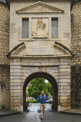 A man with a backpack walks through the historic Porte Rivotte city gate in Besançon, France,...