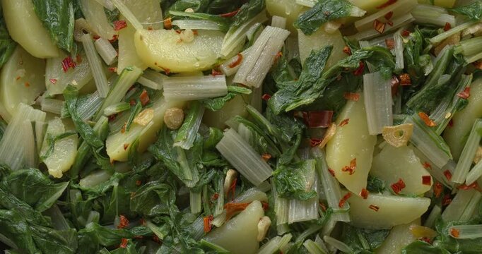Background pattern of South Croatian Blitva s Krumpirom dish. The dish is made with boiled potatoes, swiss chard, garlic, and olive oil. Table spin.