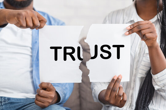 Mistrust concept. African american couple, man and woman, ripping paper with trust inscription.