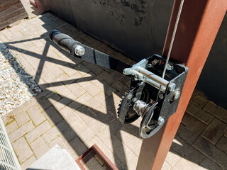 This image features a detailed close up of a heavyduty winch that is mounted securely on a sturdy wooden post, highlighting the intricate design and functionality of this mechanical device